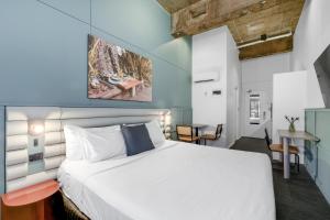 悉尼新镇城市饭店的卧室配有白色的床和桌子