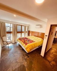 巴拉那Peatonal Suites Paraná的一间卧室配有一张床和一把椅子