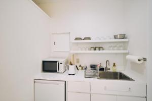 高知「まちのアトリエ」STAY UWU 004的白色的厨房配有水槽和微波炉