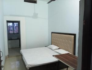 FaizābādMAHENDRA HOME STAY的一间卧室配有一张床、一张桌子和一个窗户。