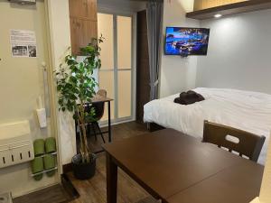 东京Cozy inn Oyama的客房设有1张床、1张桌子和1台电视。