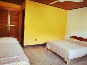 戈尔菲托La Purruja Lodge的一间卧室设有两张床和黄色的墙壁
