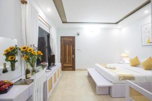 岘港Lis Hotel的白色的客房配有一张床和一张带鲜花的桌子