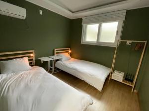 济州市hola! Hostel的绿色客房的两张床,设有窗户