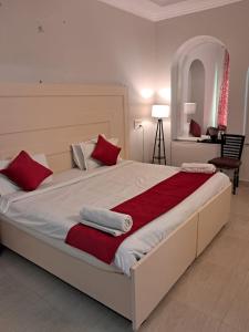 哈里瓦Hotel Bhajgovindam的一间卧室配有一张带红色和白色枕头的大床