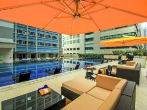 马尼拉The Mini Suites Eton Tower Makati的一个带游泳池和橙色遮阳伞的户外庭院