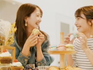长滨市AMAZING LIFESTYLE GLAMPING HOTEL - Vacation STAY 43987v的坐在桌子上吃纸杯蛋糕的两位妇女