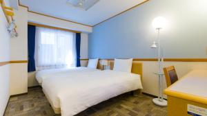 敦贺市Toyoko Inn Tsuruga Ekimae的酒店客房设有两张床和窗户。
