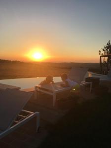 皮恩扎阿古利杜立斯莫伊玛乔内酒店的两人坐在床上,背着日落