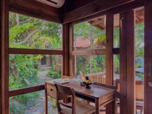 乌布Berlima Wooden Lodge by Pramana Villas的用餐室设有大窗户和木桌