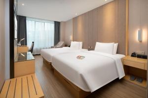 广州宜致酒店(广州珠江新城体育西路地铁站店)的一张大白色的床,位于酒店客房内