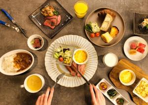 大阪LUXCARE HOTEL的餐桌,餐桌上放有盘子的食物,有人拿着用具