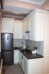 比什凯克Стильная и уютная двухкомнатная квартира.的厨房配有白色橱柜和黑色冰箱。