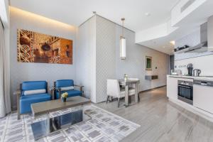 迪拜Spacious Studio Apartment in Hyatt Regency Dubai Creek Heights by the S Holiday Homes的厨房以及带蓝色椅子和桌子的客厅。