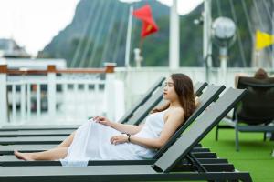 下龙湾Le Journey Calypso Pool Cruise Ha Long Bay的坐在长凳上的穿着白色衣服的女人