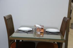 伊斯兰堡Trivelles Executive Suites Islamabad的一张桌子、两把椅子和一张桌子,桌子上放着盘子和眼镜