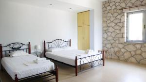 科帕罗Guest House Suga 1的一间卧室设有两张床和石墙