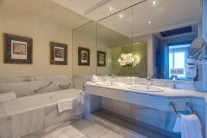 赫雷斯-德拉弗龙特拉巴瑟罗蒙蒂卡斯提罗高尔夫酒店的大型浴室设有两个水槽、一个浴缸和一个浴缸。