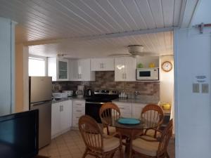 弗利盖特湾希罗夫茨海滩上酒店的一间带桌椅的厨房和一间带白色橱柜的厨房