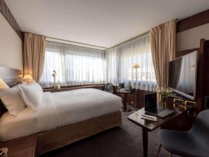 里昂索菲特里昂贝勒库尔酒店的酒店客房设有一张大床和一台电视。