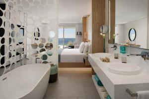 阿德耶Royal Hideaway Corales Beach - Adults Only的一间带床、浴缸和水槽的浴室