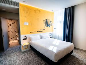 锡比乌Ibis Styles Sibiu Arsenal的一间卧室设有一张黄色墙壁的大床