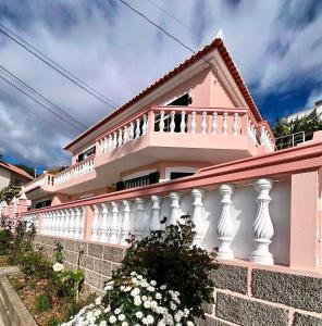 里韦拉布拉瓦Blue Paradise Apartment的粉红色的房子,有白色的围栏和鲜花