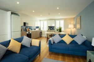 圣布雷拉德La Pulente Cottages的一间带蓝色沙发的客厅和一间厨房