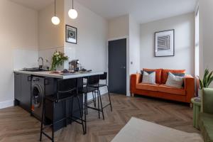 利物浦Broughton Place: Contemporary Apartments in Liverpool的厨房以及带酒吧和沙发的客厅。
