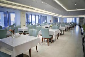 麦地那Zaha Taiba Hotel的餐厅设有白色的桌椅和窗户。