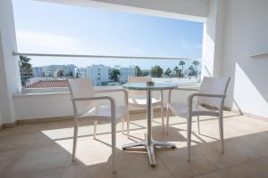 阿依纳帕New Famagusta Hotel & Suites的配有大窗户的客房内的桌椅