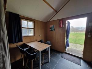 De ValomBlokhut camping De Zilveren Maan的一间带桌椅和窗户的用餐室