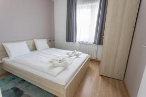 布达佩斯枫叶树经济公寓的卧室配有白色的白色床,上面有白色的鲜花