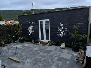 阿维莫尔Craigellachie Cabin的黑色的房子,设有种有盆栽植物的庭院