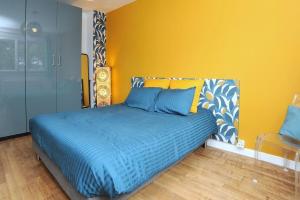 沙特尔Le Saint-Brice的一间卧室配有一张蓝色的床和黄色的墙壁