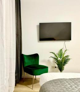 汉诺威Modernes Apartment nahe des Stadtzentrums的卧室里的绿椅,墙上配有电视