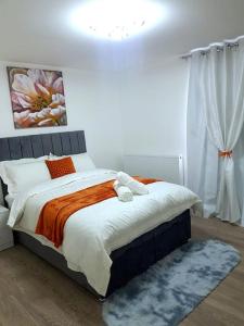 吉林汉姆Holiday Let - Entire modern home in Medway的一间卧室配有一张带橙色和白色毯子的床