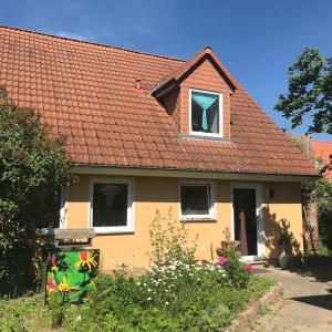 WarnitzGästezimmer in der Uckermark in Warnitz am Oberuckersee的黄色的房子,有红色的屋顶和窗户