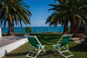 马蒂纳塔Villa Lucia的两把椅子坐在靠近海洋的草地上