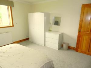邓弗里斯Annexe Meadowbank Dumfries的一间白色卧室,配有一张床和一个梳妆台
