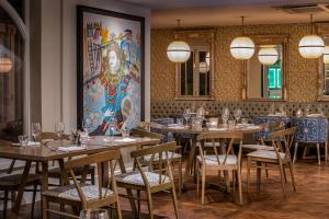 泰晤士河畔里士满Harbour Hotel & Spa Richmond的餐厅设有桌椅,墙上挂有绘画作品