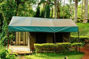 金贾Explorers River Camp的绿色帐篷,草地上设有长凳