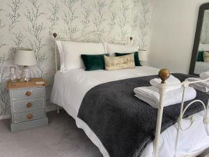 洛斯特威希尔Tiny romantic cottage for two.的卧室配有白色的床和床头柜