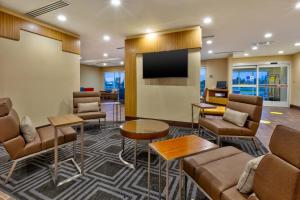 大急流城TownePlace Suites by Marriott Grand Rapids Airport Southeast的大堂设有带椅子和平面电视的等候室