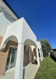 普拉Residenza del Barone Luxury House - Pula, Sardegna的白色柱子和草坪的房子