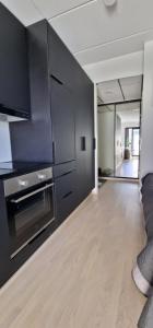 坦佩雷Modern apartment near Tampereen Messukeskus, with own private and free parking的厨房配有黑色橱柜和木地板