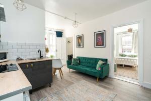 伦敦Shoreditch-bricklane-convenient-central-liverpoolstreet的厨房以及带绿色沙发的起居室。