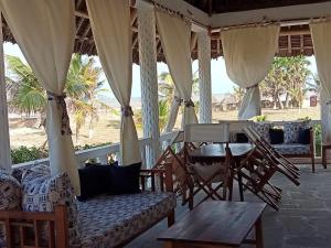 马林迪Karibuni Villa - Malindi beach view property的海滩上带椅子和桌子的门廊