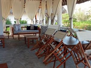马林迪Karibuni Villa - Malindi beach view property的庭院里摆放着几把椅子和桌子
