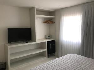 皮帕GIRASSÓIS - Suítes的一间卧室配有电视、一张床和一个窗户。